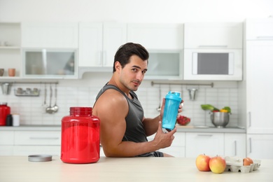 Photo of Young athletic man with ingredients for protein shake in kitchen