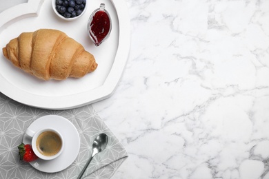 Photo of Tasty breakfast with fresh croissant and aromatic coffee on white marble table, flat lay. Space for text