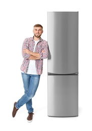 Young man near closed refrigerator on white background