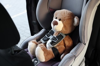 Photo of Teddy bear in child safety seat inside car