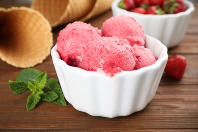 Photo of Bowl with delicious strawberry ice cream on wooden table, closeup