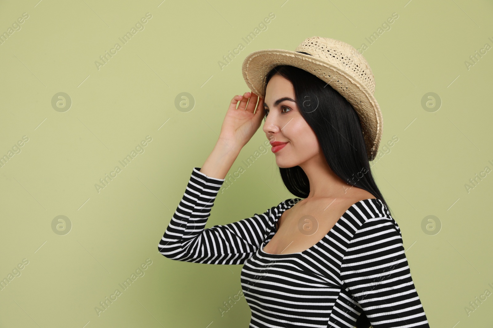 Photo of Beautiful young woman with straw hat on light green background. Space for text