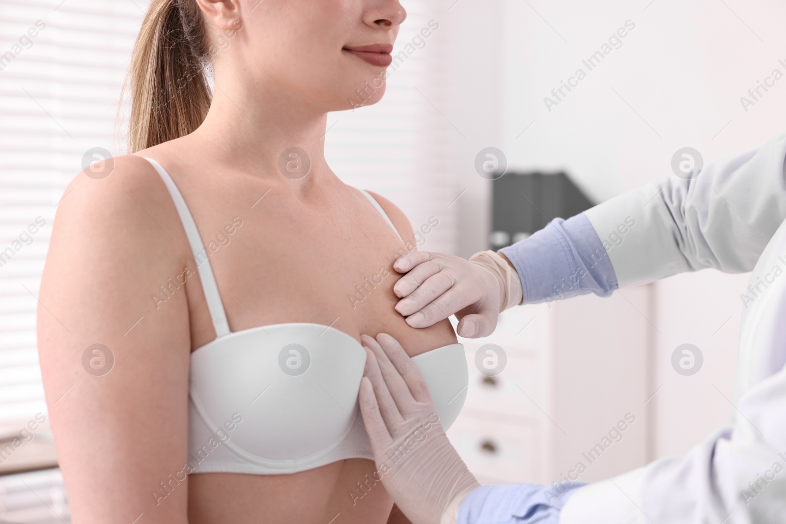 Photo of Mammologist checking woman's breast in hospital, closeup