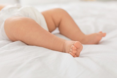 Cute little baby lying on bed, closeup of legs