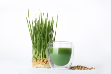 Photo of Fresh wheat grass juice in glass, seeds and sprouts on white background