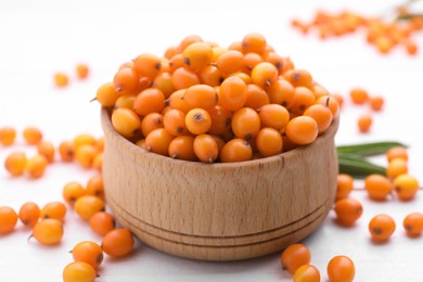 Photo of Bowl with fresh ripe sea buckthorn berries on white wooden table, closeup