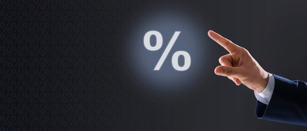 Image of Mortgage. Man pointing at percent sign on dark grey background, closeup. Banner design with space for text