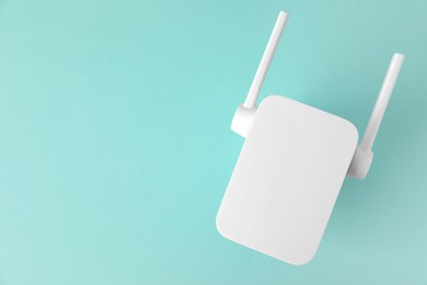 Photo of New modern Wi-Fi repeater on turquoise background, top view. Space for text
