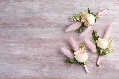 Photo of Small stylish boutonnieres on light wooden table, top view. Space for text