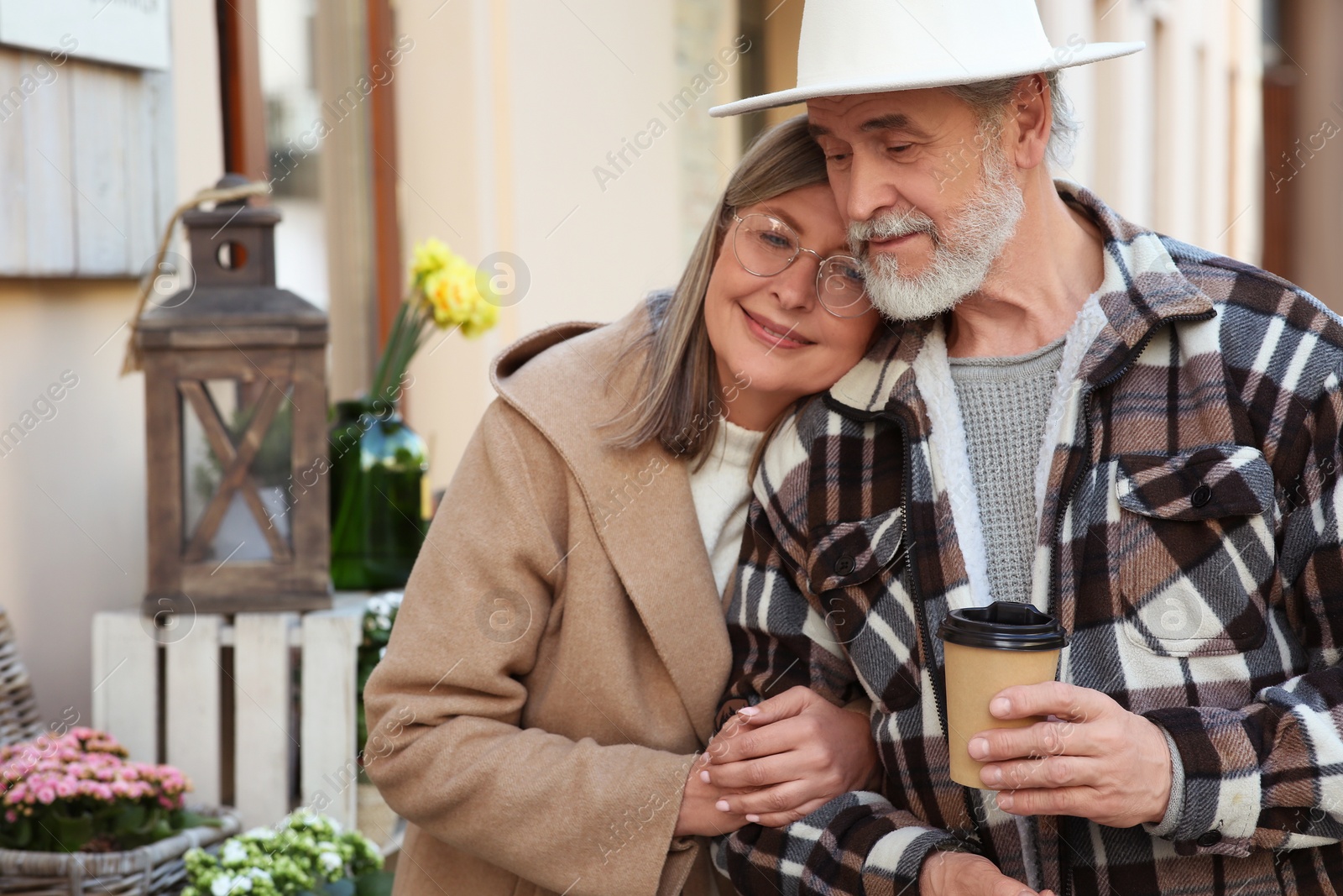 Photo of Affectionate senior couple drinking coffee outdoors, space for text