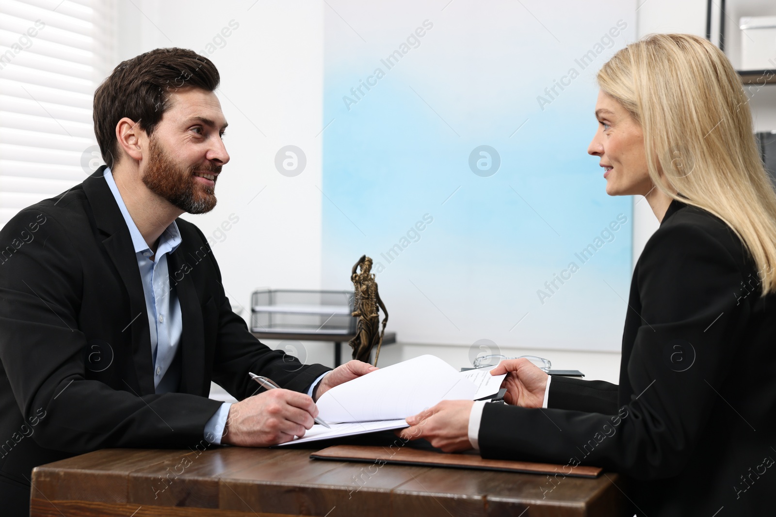 Photo of Man signing document at table in lawyer's office