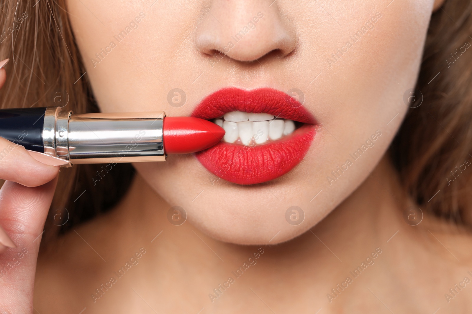 Photo of Young woman holding red lipstick, closeup view