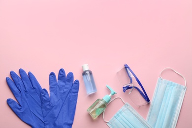 Flat lay composition with medical gloves, masks and hand sanitizers on pink background. Space for text