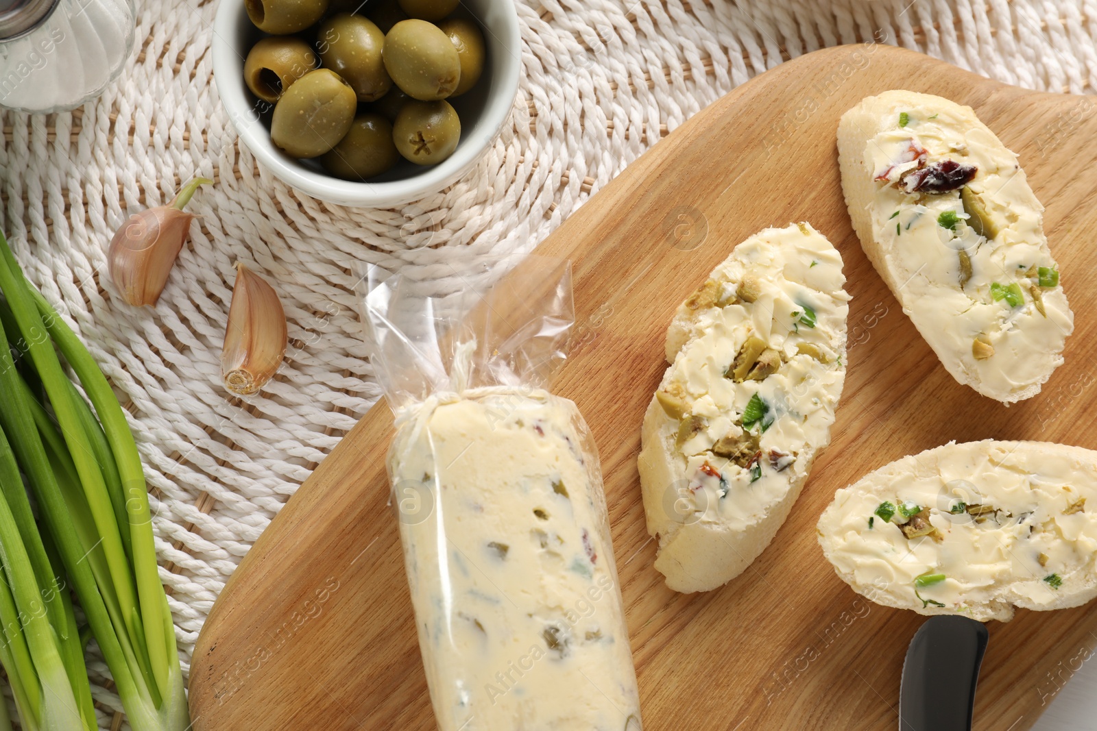 Photo of Tasty butter with olives, green onion, garlic and bread on table, top view