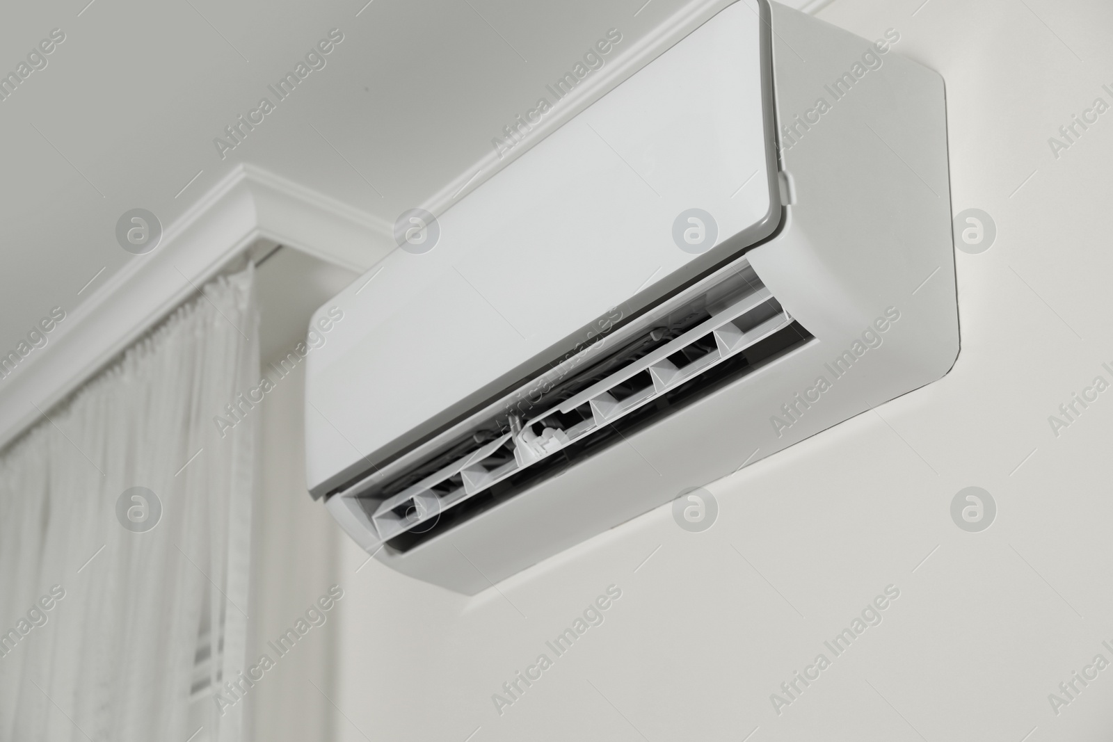 Photo of Modern air conditioner on white wall indoors