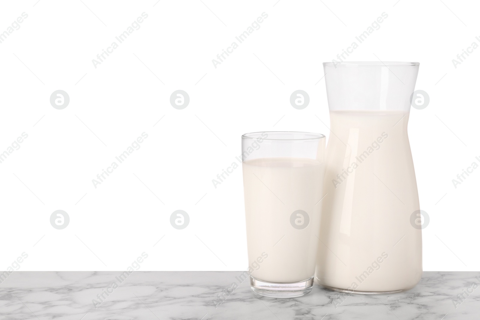 Photo of Glassware with tasty milk on marble table against white background