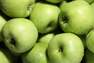 Fresh green apples with water drops as background, top view