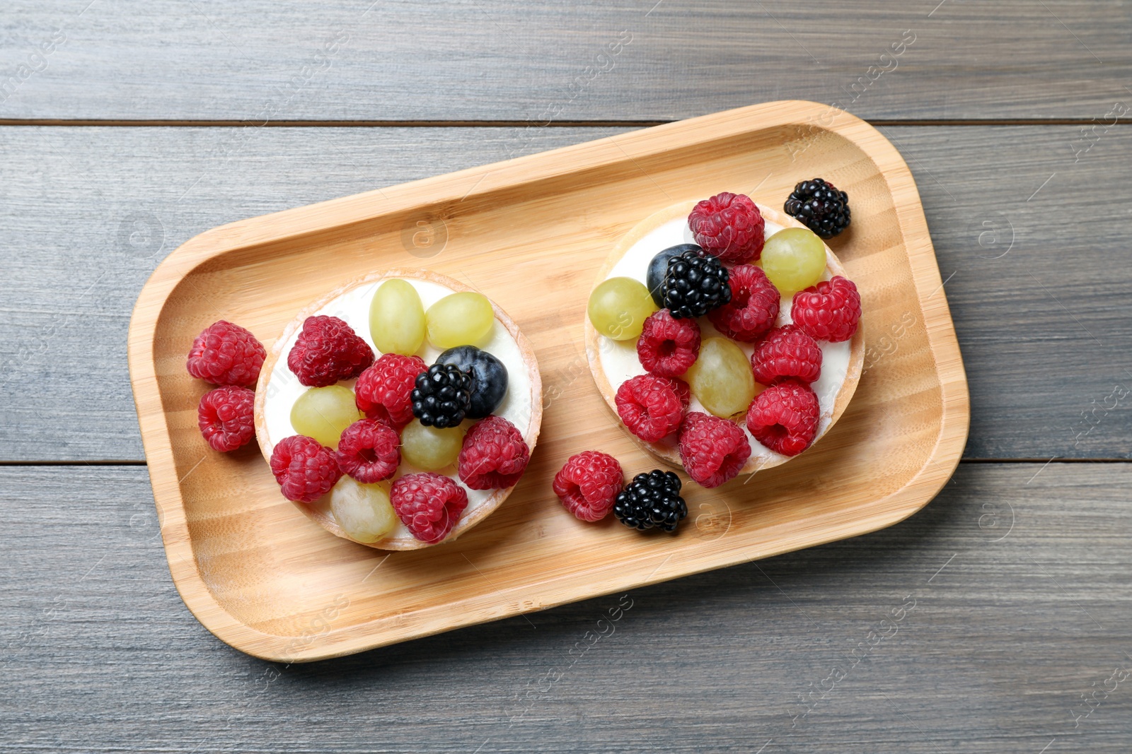 Photo of Delicious tartlets with berries on wooden table, top view