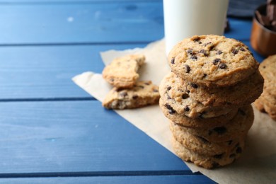 Photo of Tasty chocolate chip cookies and glass of milk on blue wooden table, closeup. Space for text