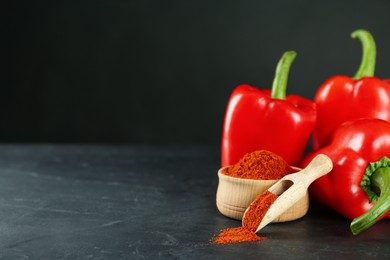 Photo of Paprika powder and fresh bell peppers on black table. Space for text