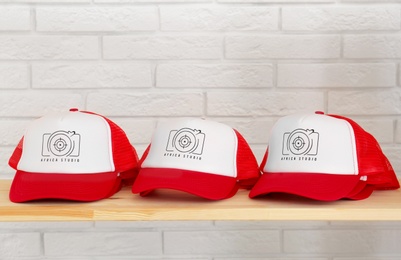 Red and white caps with logo on wooden shelf in shop