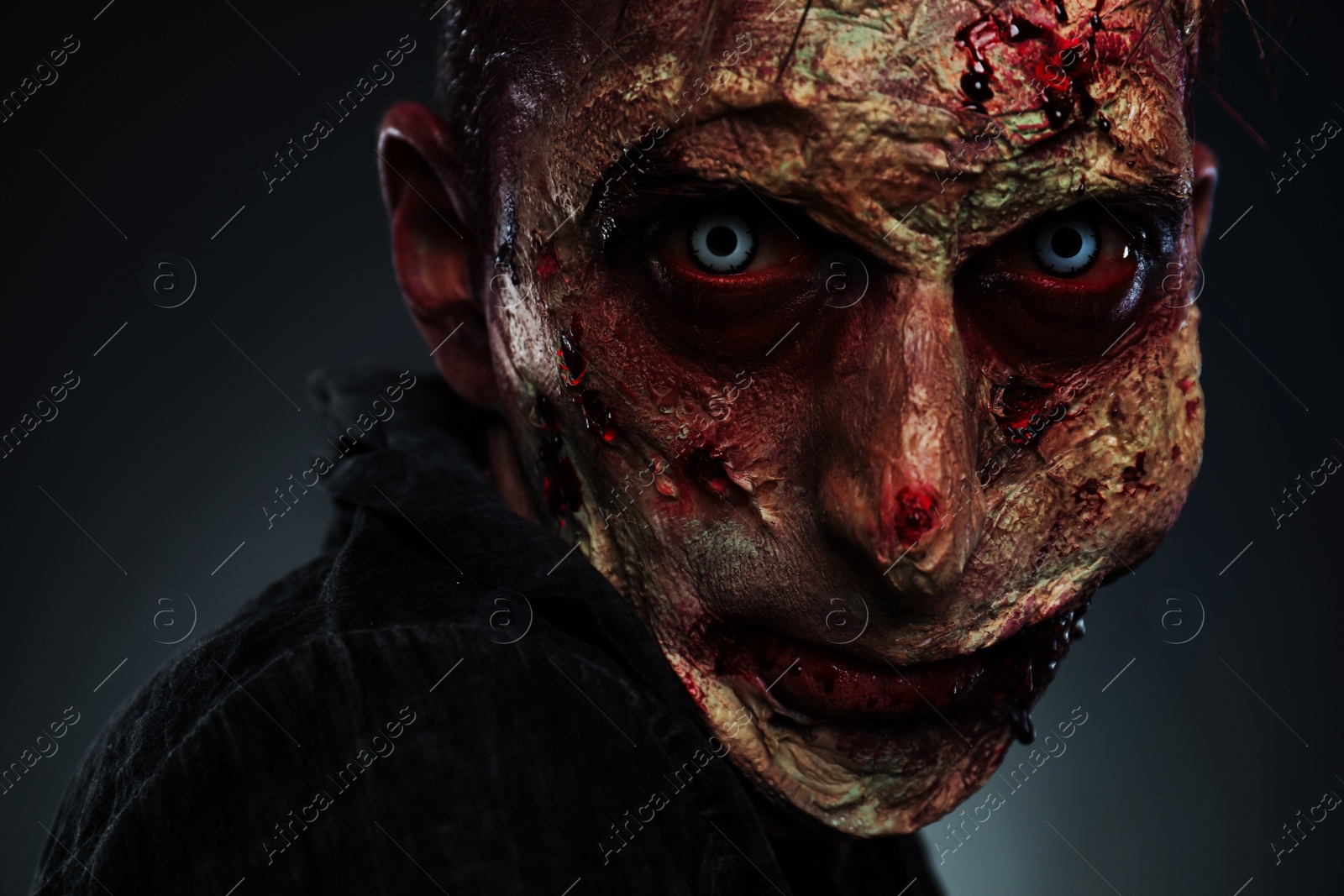 Photo of Scary zombie on dark background, closeup. Halloween monster