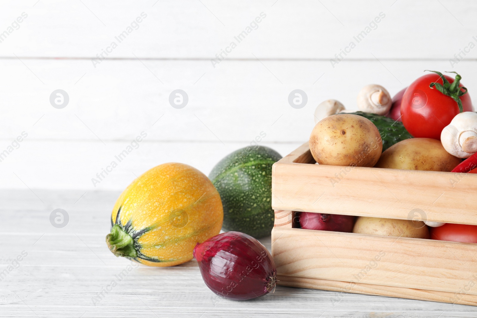 Photo of Wooden crate full of fresh vegetables on table. Space for text