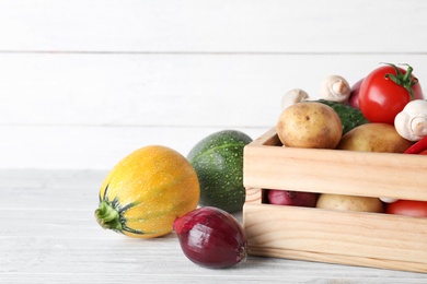 Wooden crate full of fresh vegetables on table. Space for text