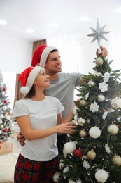 Photo of Couple decorating Christmas tree with star topper indoors