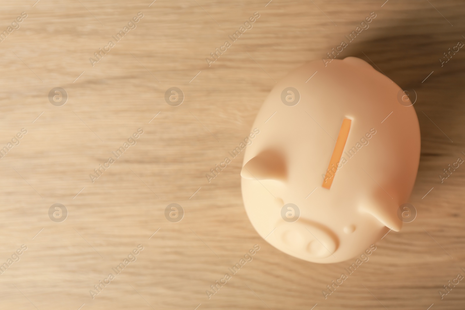 Photo of Ceramic piggy bank on wooden table, top view. Space for text