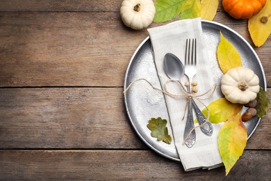 Seasonal table setting with pumpkins and other autumn decor on wooden background, flat lay. Space for text