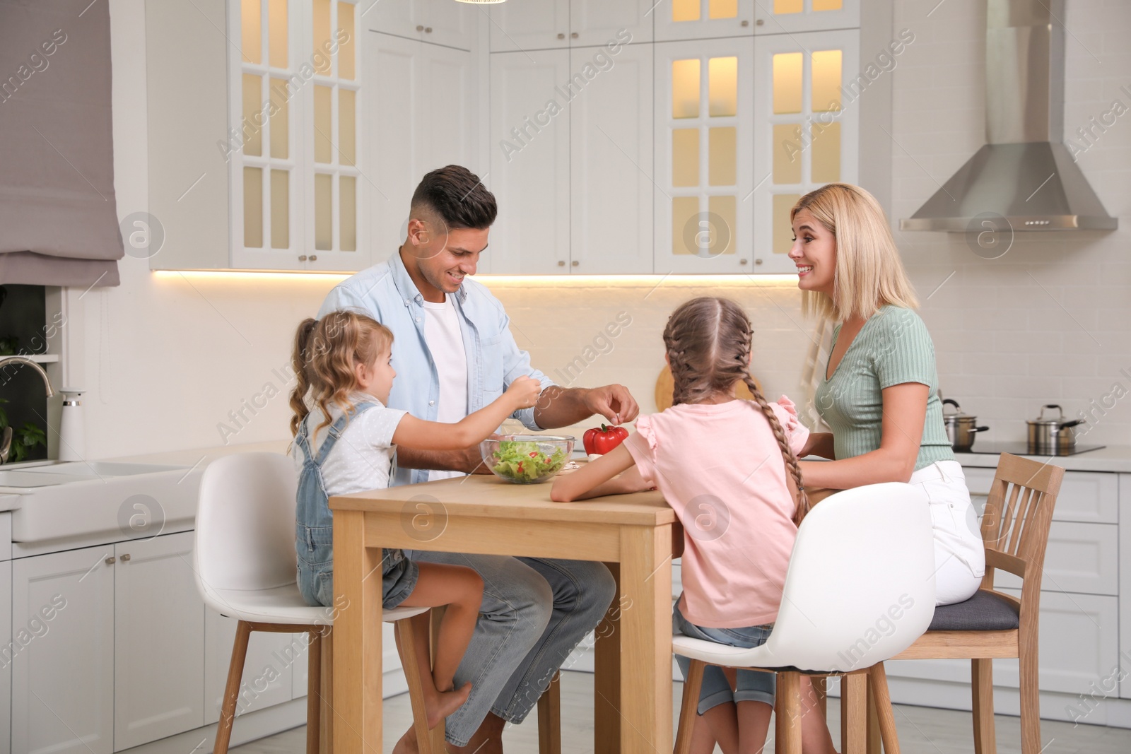 Photo of Happy family cooking together at table in modern kitchen