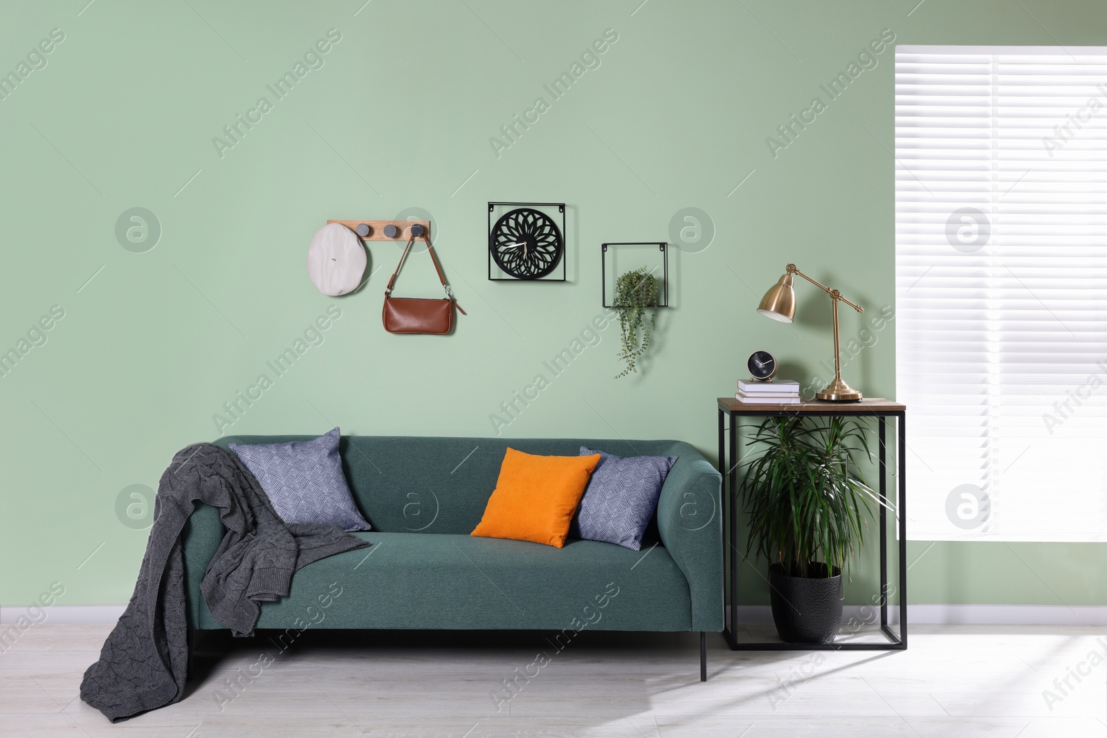 Photo of Stylish interior with comfortable sofa, blanket and cushions near console table