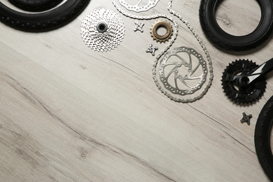 Photo of Set of different bicycle parts on wooden background, flat lay. Space for text