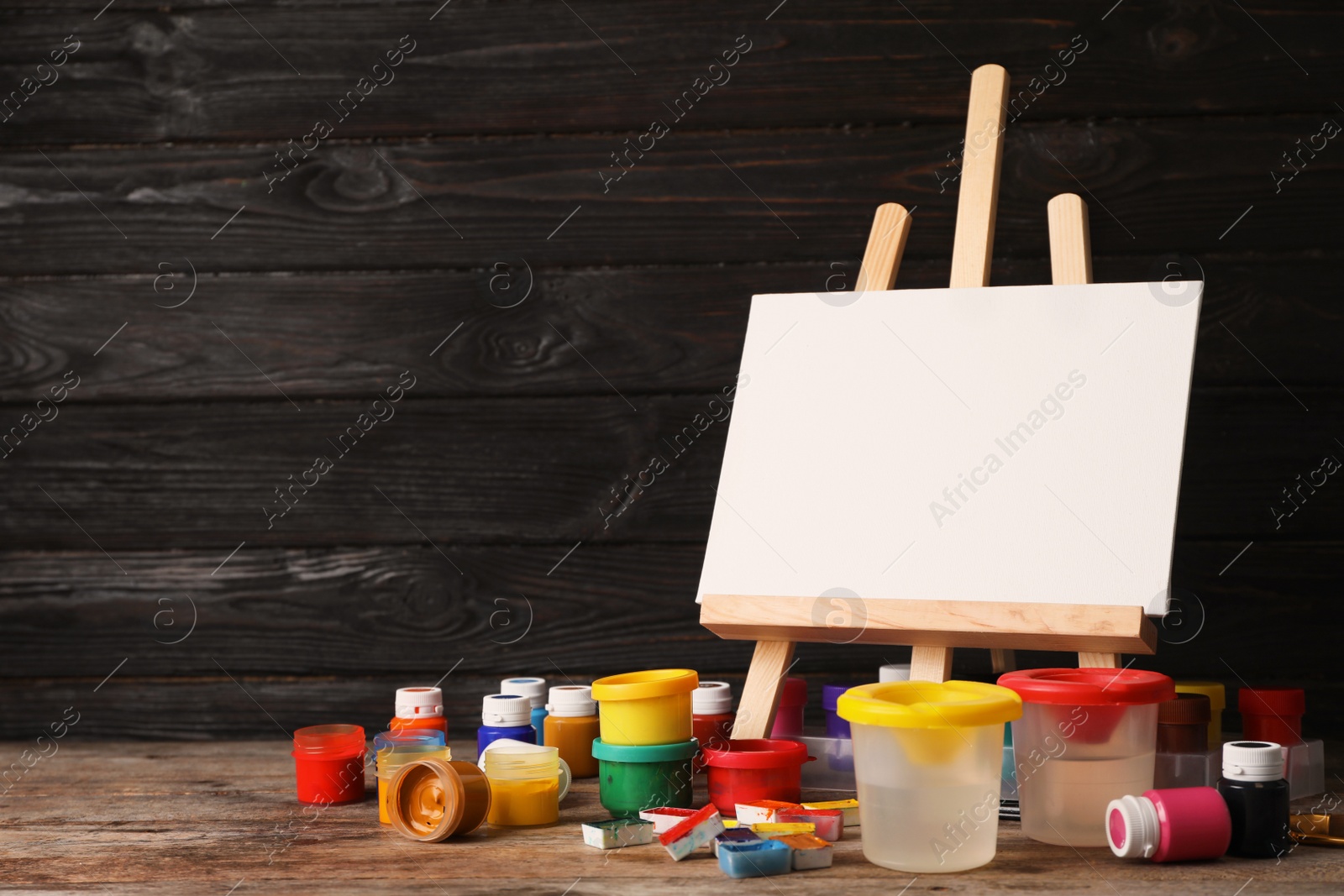 Photo of Set of painting materials for child on table near wooden wall. Space for text