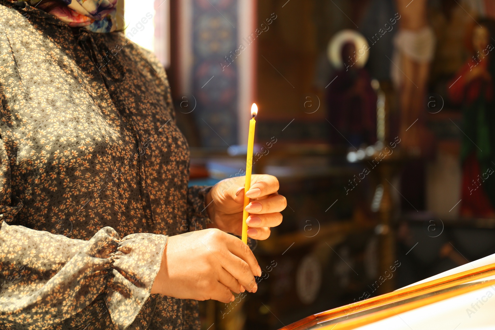 Photo of Mature woman holding candle in church, closeup