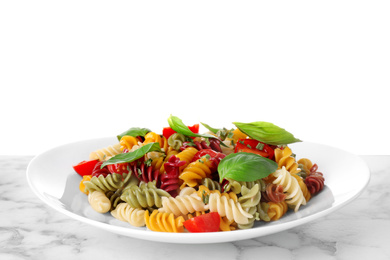 Photo of Colorful pasta with basil and cherry tomatoes on marble table against white background