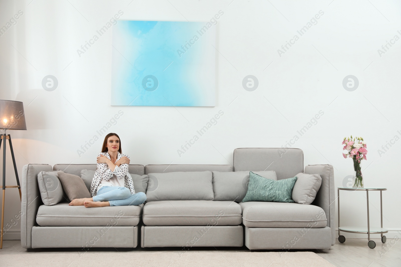 Photo of Young woman freezing under air conditioner at home