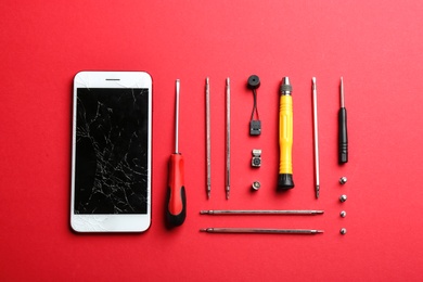 Photo of Flat lay composition with broken mobile phone and repair tools on color background