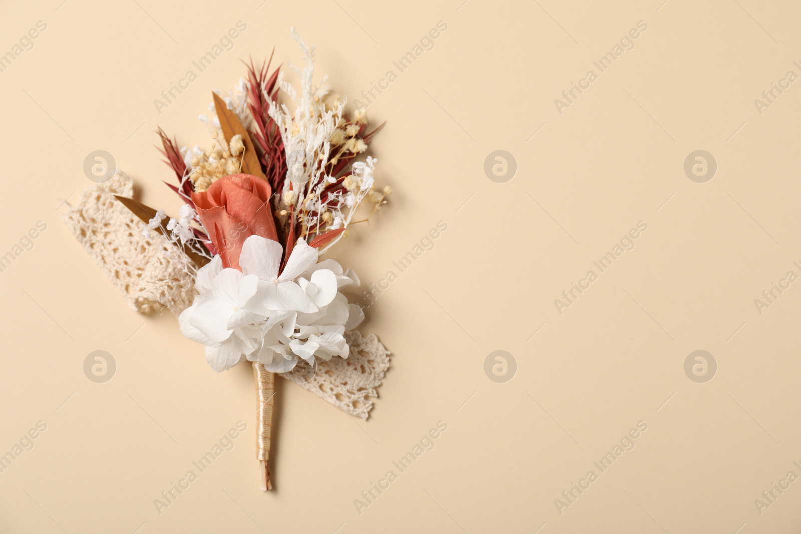 Photo of Stylish boutonniere on beige background, top view. Space for text