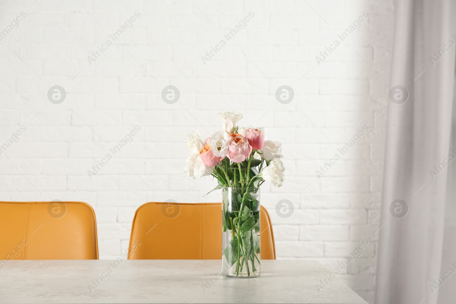 Photo of Vase with beautiful flowers as element of interior design on table in room