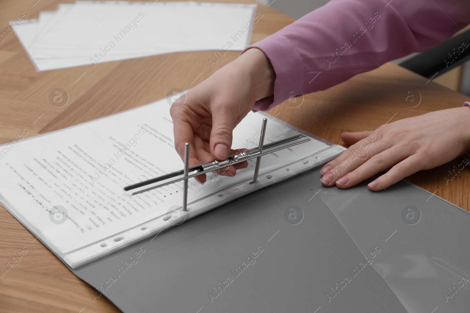 Photo of Woman fixing folder with punched pockets at wooden table, closeup