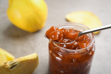 Delicious quince jam on grey table, closeup