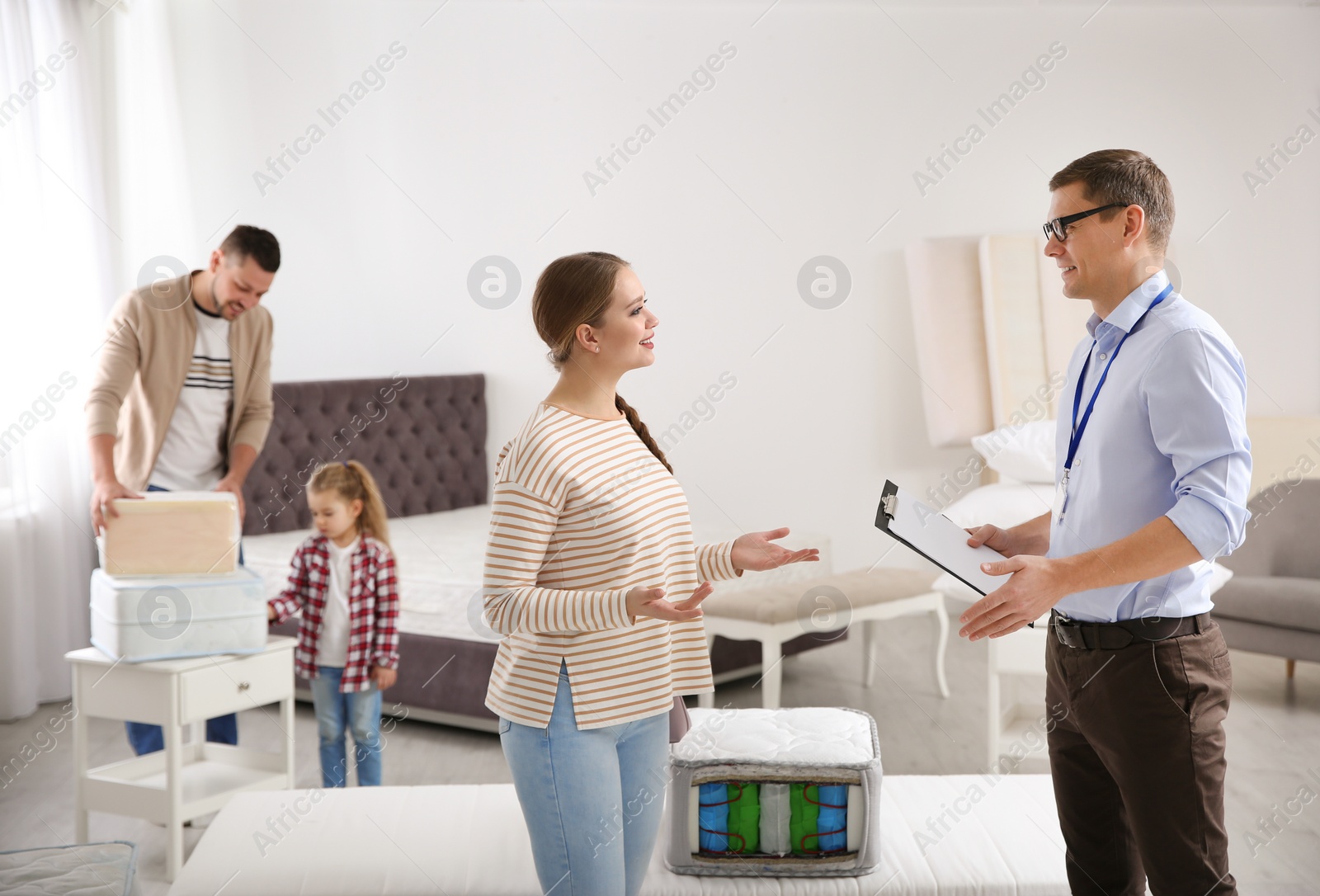 Photo of Salesman consulting young woman in mattress store