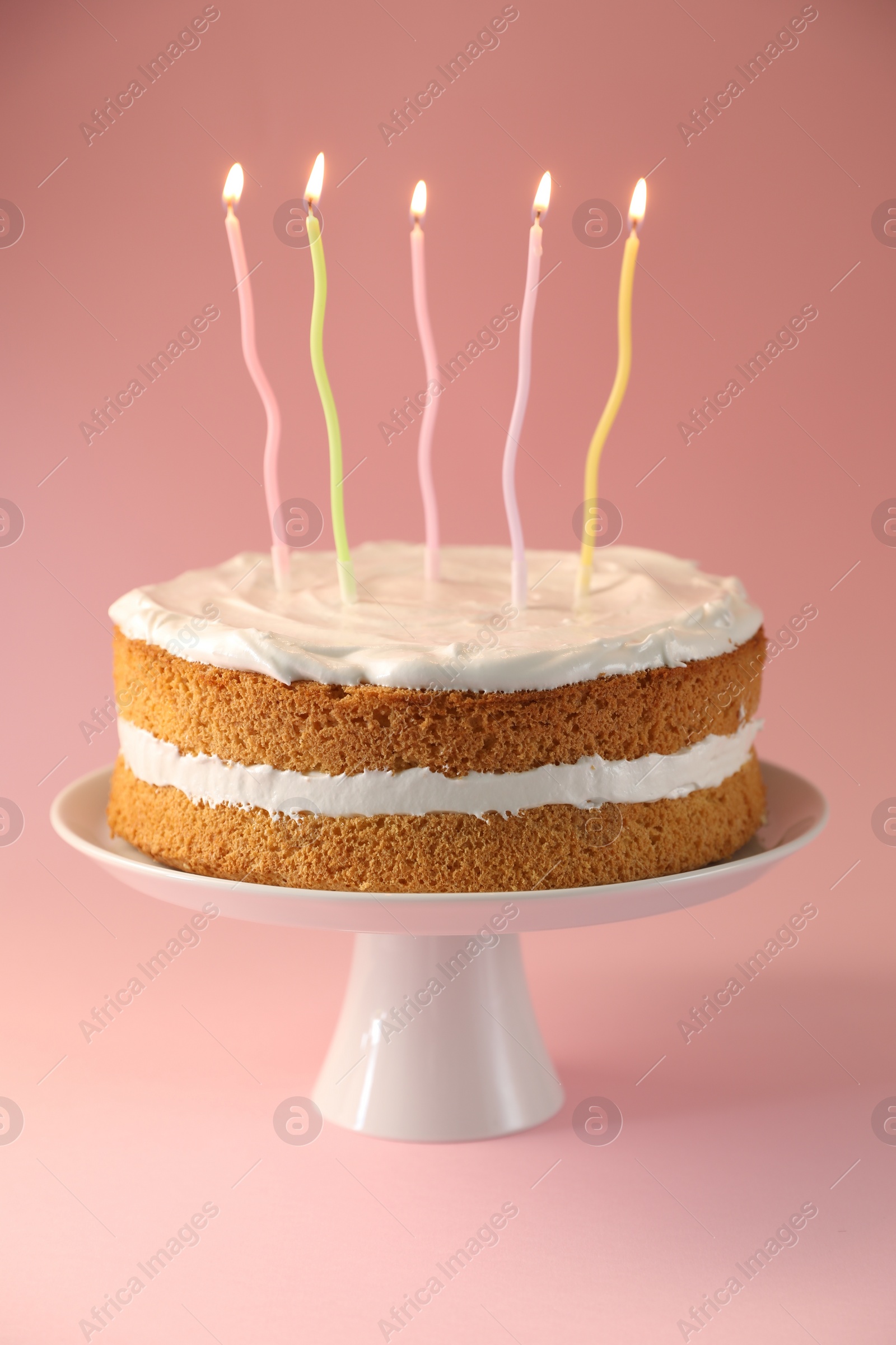 Photo of Tasty cake with colorful candles on pink background