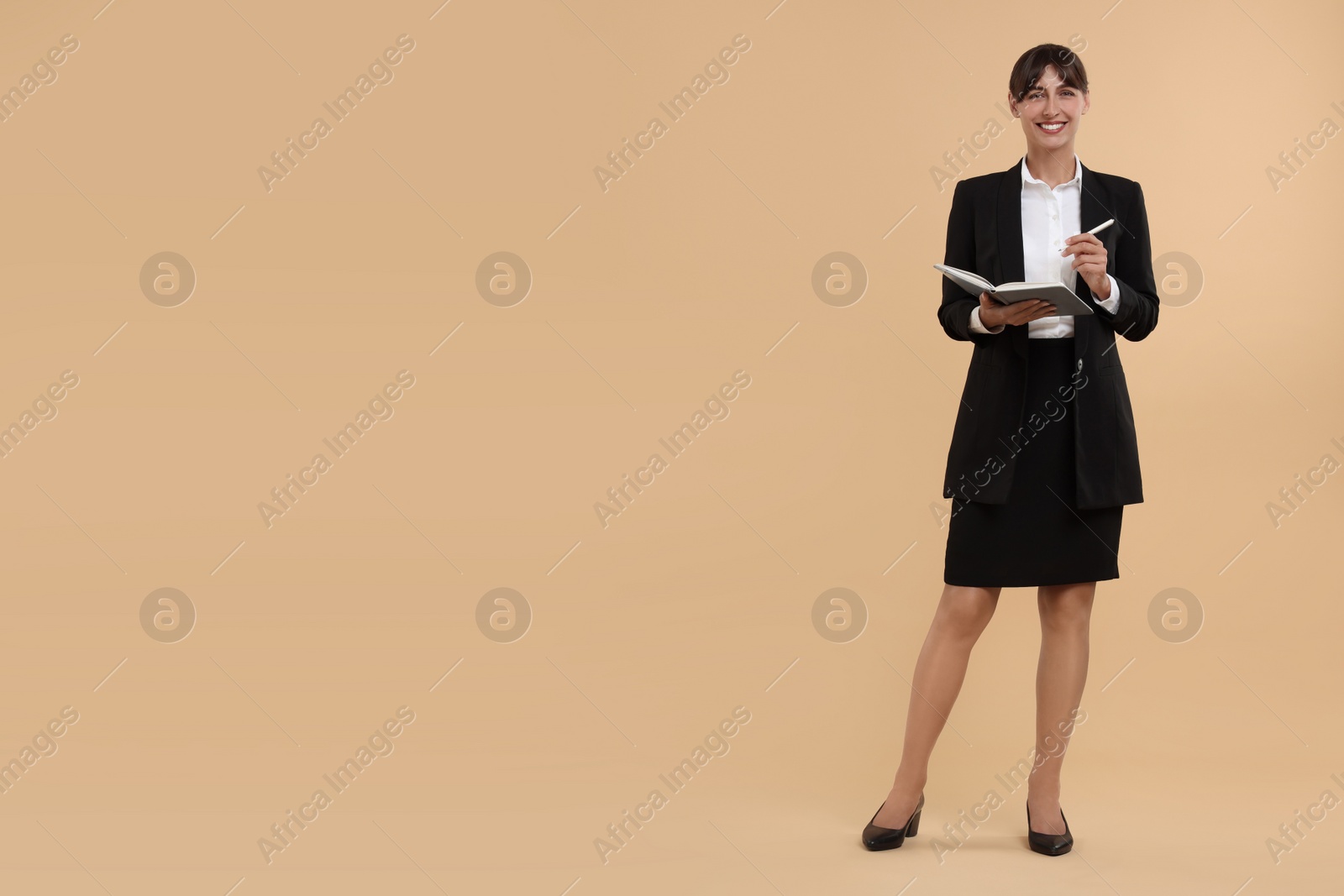 Photo of Happy secretary with notebook and pen on beige background. Space for text