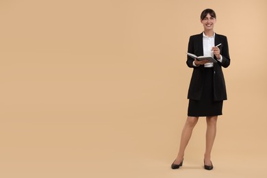 Happy secretary with notebook and pen on beige background. Space for text