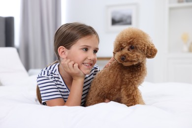 Photo of Little child and cute puppy on bed at home. Lovely pet