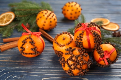 Photo of Pomander balls made of fresh tangerines and cloves on blue wooden table