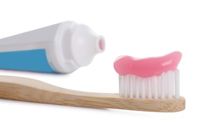 Photo of Wooden brush with toothpaste and tube on white background, closeup